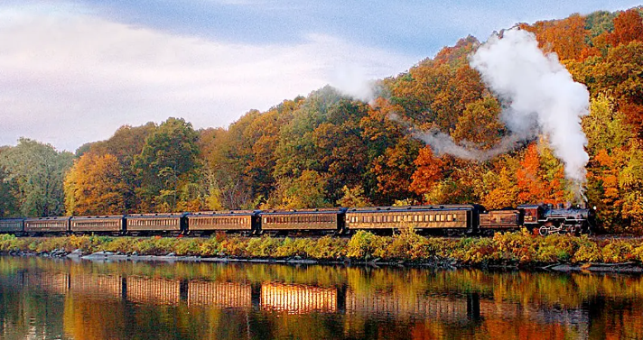 CT Essex Train on tracks surrounded by colorful fall foliage and trees.